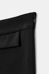 Pantalón capri de tiro medio en color negro, con detalles de tapetas frontales, aberturas laterales en el bajo y cierre lateral con cremallera oculta.