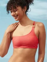 Bikini de una pieza con diseño de un solo hombro, confeccionada en tela texturizada color salmón. Presenta un detalle de argolla decorativa en el hombro y copas removibles.