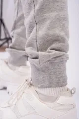 Pantalón de jogging color gris oscuro con efecto lavado, confeccionado en frizza de algodón. Presenta un diseño relajado con bolsillos laterales y un detalle bordado de alas en la parte frontal.