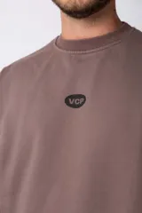 Buzo de cuello redondo y corte oversize, confeccionado en frisa suave. Presenta un diseño minimalista en color negro con un pequeño logo ovalado en el centro del pecho y una estampa sutil en el lateral inferior derecho.