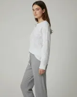 Pijama compuesto por una remera de manga larga con estampado floral sutil y cierre frontal de botones, y un pantalón de corte recto en color gris con cintura elástica ajustable.