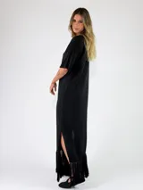 Vestido largo bordó de punto metalizado, con escote en V, mangas cortas y detalle de flecos en el ruedo.