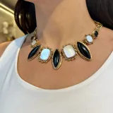 Collar de bronce con piedras naturales engarzadas. Presenta piedras rectangulares blancas nacaradas y piedras ovaladas negras, todas con bordes dorados texturizados.