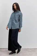 Camisa de manga larga a rayas verticales azul marino y blancas, con cuello clásico, bolsillo de parche en el pecho y ribetes finos en color rojo.