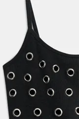 Top crop negro de escote redondo y tirantes finos, con detalle de arandelas metálicas distribuidas en la parte frontal.
