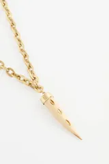 Collar largo de cadena de eslabones gruesos en tono dorado con dije colgante en forma de colmillo de hueso con casquillo metálico.