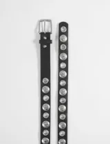 Cinturón de cuero sintético negro con diseño de tachas metálicas circulares grabadas y ojalillos metálicos a lo largo de toda la tira. Incluye hebilla metálica plateada.