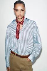 Jeans de tiro alto color azul oscuro, con cinco bolsillos, pernera ancha y nervio marcado en el delantero. Incluye un cinturón fino de cuero sintético marrón con textura de cocodrilo. Cierre frontal con cremallera y botón.