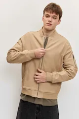 Campera bomber de gabardina color tostado, con cierre frontal y bolsillos laterales, puños y cintura elastizados de rib.