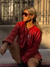 Camisa de cuero sintético color rojo, con cierre frontal de botones, cuello clásico y mangas largas con puños fruncidos y volados.