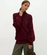 Suéter de punto color bordó con cuello alto, mangas largas amplias con puños ajustados y diseño de corte largo con terminación acanalada en el ruedo.