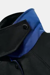 Chaqueta de Zara Woman Collection color negro, de cuello con solapa y manga larga. Cuenta con bolsillos delanteros ocultos en las costuras, cierre frontal con botones metálicos a presión y detalle de diseño asimétrico en azul en el cuello.