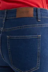 Pantalón de jean azul oscuro, de corte cropped y acampanado, con ruedo desflecado.