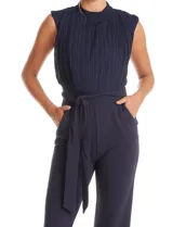 Enterito de crepe color azul marino, con torso plisado sin mangas y cuello alto. Presenta corte en la cintura con lazo de ajuste y pantalón de pierna recta con bolsillos funcionales.