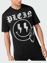 Camiseta negra de manga corta con cuello redondo, confeccionada en algodón. Presenta un estampado frontal con el logo de la marca, un smiley con rayos en los ojos y un dedo medio levantado, decorado con strass.