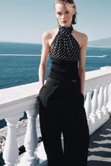 Top de cuello halter con hombros descubiertos, confeccionado con una combinación de tejidos. La parte superior presenta un estampado de lunares, mientras que la parte inferior es de tejido liso acanalado.