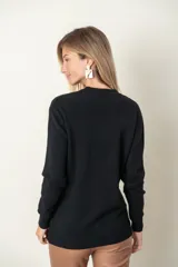 Sweater gris de punto con cuello redondo y mangas largas. Presenta diseño trenzado en el frente y dos bolsillos delanteros.