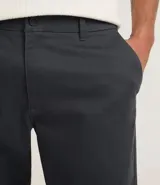 Pantalón de corte recto confeccionado en sarga de algodón con un toque de elastano. Presenta cintura con trabillas para cinturón, cierre tradicional de botón y cremallera, y bolsillos laterales y traseros.