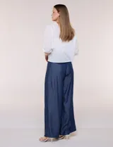 Cardigan corto de broderie blanco con escote en V y cierre frontal de lazos para anudar. Presenta mangas tres cuartos abullonadas con puño elástico y diseño perforado con motivos florales.