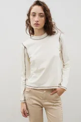 Remera de cuello alto y manga larga en color crudo, con costuras a la vista en contraste de color marrón.