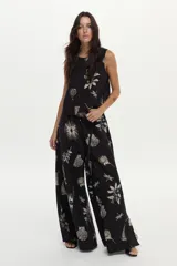 Pantalón palazzo negro con estampado artesanal en tonos claros, cintura elastizada, bolsillos laterales y aberturas en las piernas.