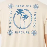 Remera de manga corta color beige, con cuello redondo y estampado pequeño en el pecho que incluye palmeras y el logo de la marca Rip Curl.