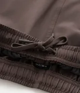 Bermuda deportiva gris con cintura elástica, cordón de ajuste, bolsillos con cremallera, recorte lateral con agujeritos y abertura en el bajo.