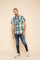 Camisa de manga corta con estampado de cuadros en tonos verdes, azules y blancos. Presenta cuello clásico, cierre frontal con botones y dos bolsillos delanteros con solapa.