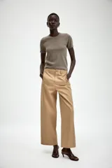 Pantalón de sarga en color beige, con tiro medio, cintura con trabillas y pernera recta. Presenta bolsillos de vivo en el delantero, cierre frontal con cremallera y botón metálico.