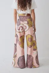 Pantalon de corte wide leg y tiro alto, confeccionado en tela con estampado deportivo que incluye pelotas de futbol y raquetas de tenis en tonos verde, rosa y beige.