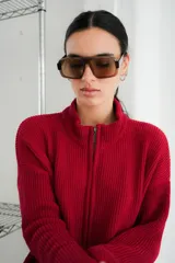 Campera tejida con textura vanizada a rayas horizontales en blanco y negro, con cierre frontal y flecos negros en forma de V en el pecho.