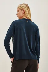 Sweater de punto en color azul oscuro, con cuello redondo y mangas largas. Presenta un diseño frontal completamente cubierto de lentejuelas brillantes en tonos azulados y verdosos.