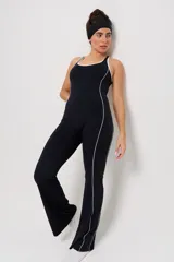 Mono deportivo de una pieza en color negro, con diseño de corte ajustado en el torso y piernas ligeramente acampanadas. Presenta detalles de líneas blancas contrastantes a lo largo de los laterales y en el escote, con espalda estilo nadadora.
