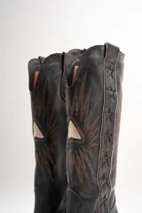 Botas texanas de cuero color marrón con bordados blancos en forma de estrellas y rayos.