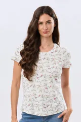 Remera de manga corta con cuello redondo, confeccionada en algodón con estampa de diseño floral en tonos rosados y verdes sobre base beige.