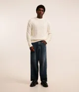 Pantalón de jean azul oscuro, corte amplio tipo skater, con bolsillos delanteros y traseros, y cierre con botón y cremallera.