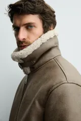 Cazadora de corte regular fit confeccionada en tejido efecto piel color marrón, con interior de borreguillo a contraste. Presenta cuello solapa con trabilla, cierre frontal de cremallera, bolsillos de vivo en la cadera y puños y bajo acabados en rib.