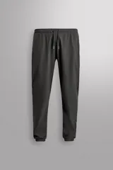 Pantalón de jogging negro confeccionado en tejido técnico ligero y elástico, corte slim fit, con cintura elástica ajustable con cordón, bolsillos laterales y trasero con cierre de cremallera, bandas reflectantes en las piernas y bajos ajustables con cremallera.