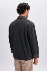 Campera gris oscuro de lona, con cuello camisero de pana en tono contrastante y cierre frontal con cremallera metálica.