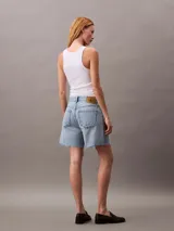 Short de jean de tiro alto con diseño de cinco bolsillos, cierre de cremallera y botón, con detalles de roturas y ruedo deshilachado.