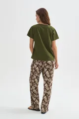 Remera de algodón verde militar, de manga corta y corte holgado, con cuello redondo a la base y detalle de cinta perforada en los hombros.