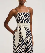 Mono largo de sastrería marca Cortelle, confeccionado en crepé con elastano, con estampado animal print de cebra en tonos beige y negro. Presenta escote recto, tirantes finos regulables, corte wide leg en las piernas y un cinturón ancho ajustable en la cintura.