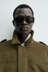 Cazadora cropped fit color verde militar, confeccionada en tejido efecto ante. Cuenta con cuello solapa, manga larga con puño abotonado, trabillas en los hombros, bolsillos laterales ocultos y un bolsillo interior. El bajo tiene elástico interior y el cierre frontal es con cremallera oculta por solapa con botones a presión.