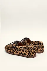 Mocasín tipo boat shoe color marrón, confeccionado en cuero, con cordones de cuero marrón y cordones decorativos azules.