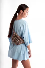 Riñonera color beige con textura de piel de cocodrilo, correa ajustable y cierre con cremallera.