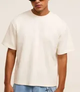 Remera masculina color blanco hueso, modelo boxy, con cuello redondo y mangas cortas. Confeccionada con tecnología Dry para un tacto frío en el interior y algodón en el exterior.