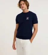 Remera azul marino de viscosa con cuello redondo y mangas cortas. Presenta un bordado con motivos marineros en el frente. Corte regular.