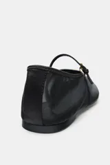 Bailarina plana color negro, confeccionada en malla transparente (mesh) con punta redonda. Posee una tira fina con hebilla que cruza el empeine y un adorno metálico dorado con forma orgánica en la punta.