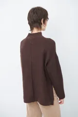 Polera de tejido de punto color chocolate, con cuello alto, mangas largas con puños acanalados y detalle de costura central vertical. Incluye una pequeña etiqueta de cuero sintético en el ruedo.