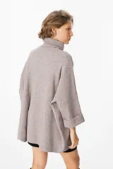 Sweater de tejido de punto suave en color beige, con silueta holgada, cuello alto y mangas tres cuartos con puños definidos.